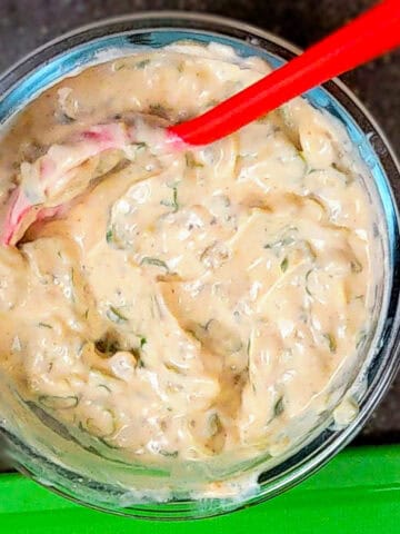 cholula green chli sour cream in a glass bowl with a spoon.