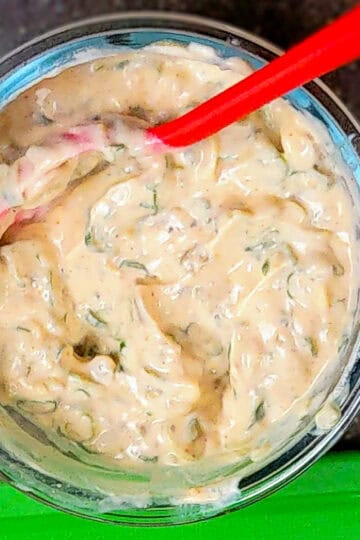 cholula green chli sour cream in a glass bowl with a spoon.