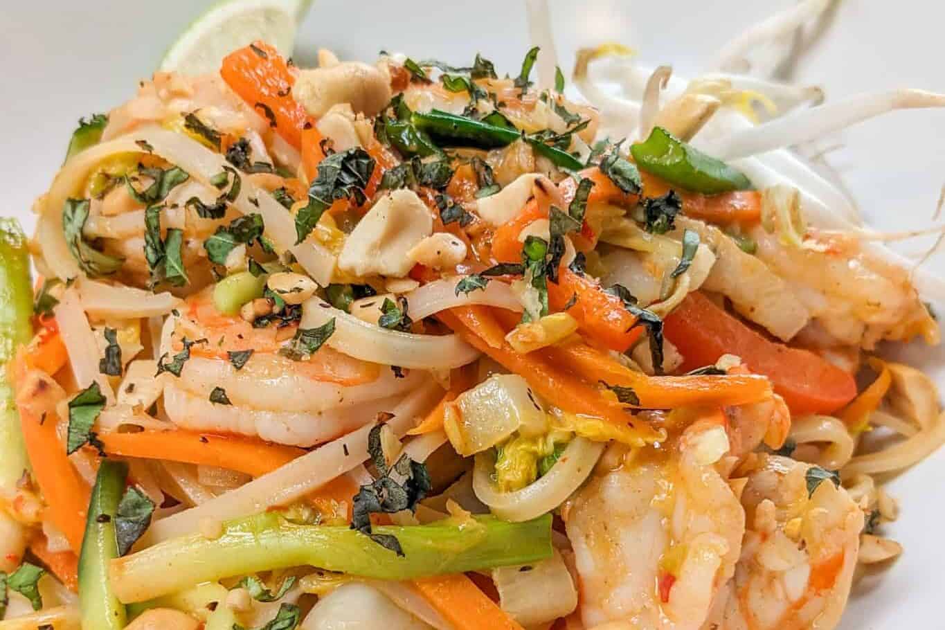 side view of the Shrimp and Pork Belly Pad Thai - Spring Roll Style in a wide rim bowl.