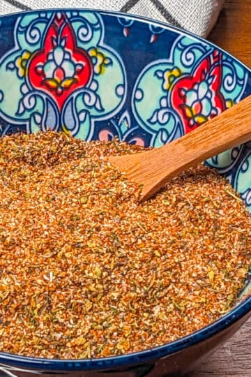 all purpose steak seasoning in a decorated bowl with a wooden spoon.