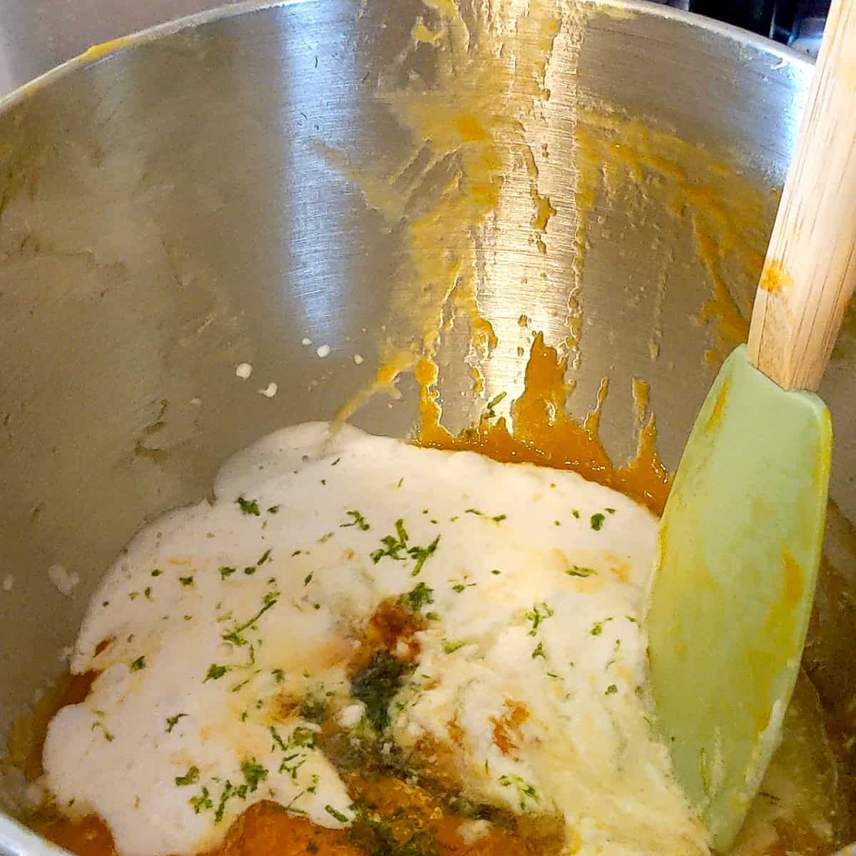 mango puree with coconut milk, lime zest and other ingredients with a spatula.