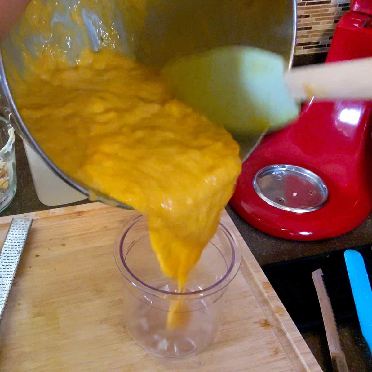 mango puree being poured in a ninja creami pint.