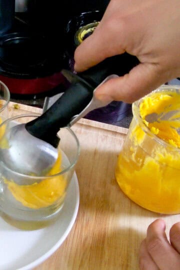 gelato being scooped into glass cups.