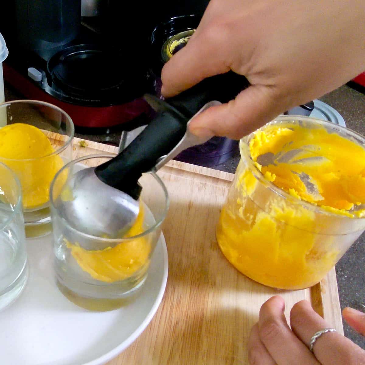 gelato being scooped into glass cups.