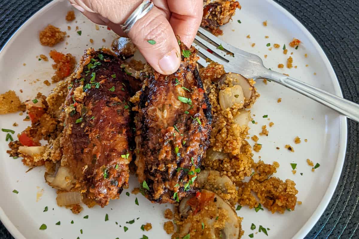 Spicy Peanut Chicken Wings with Mushroom Jollof Fonio Pilaf on a plate.
