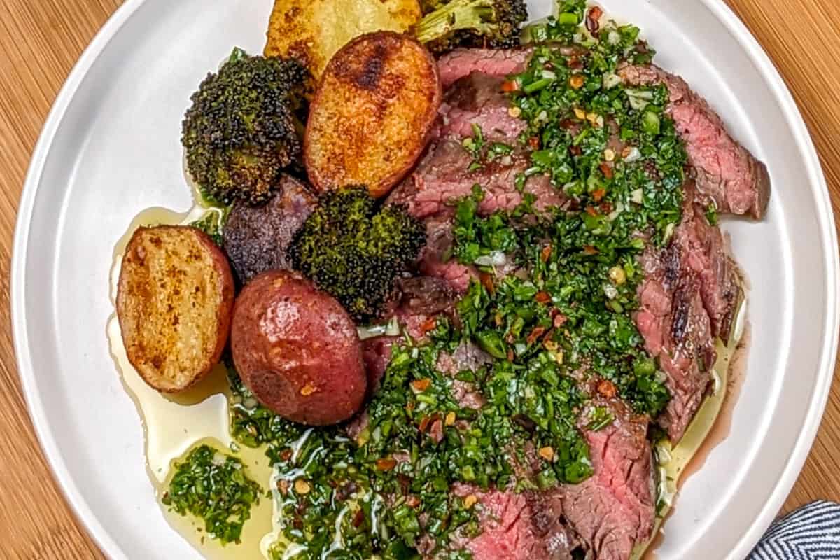 sliced steak topped with fresh chimichurri with roasted potatoes on the side. 