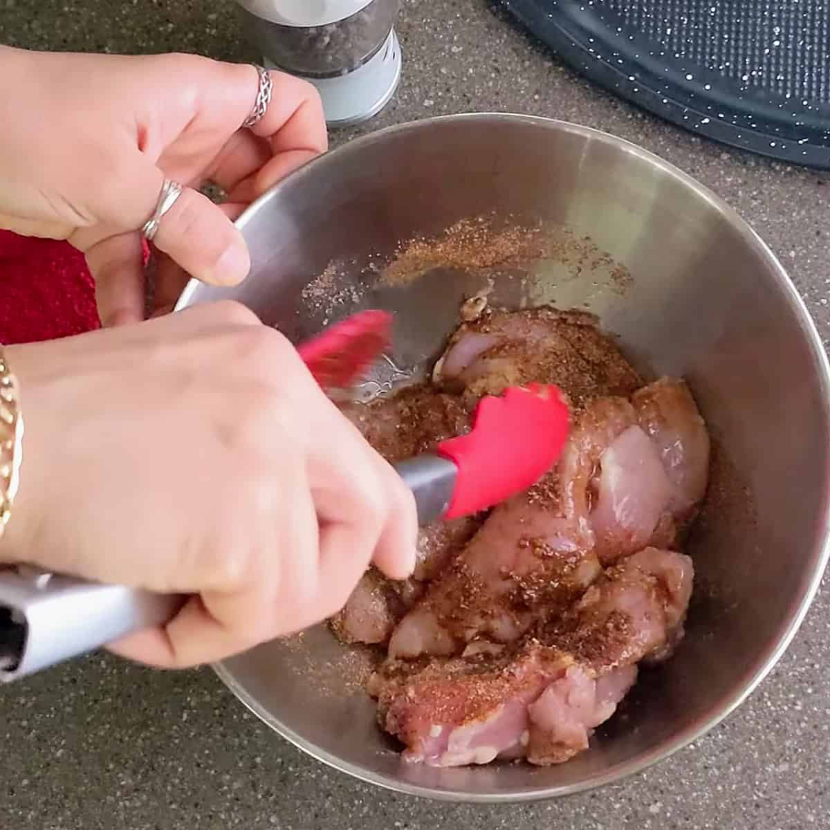 seasoned chicken being mixed with a spoon.