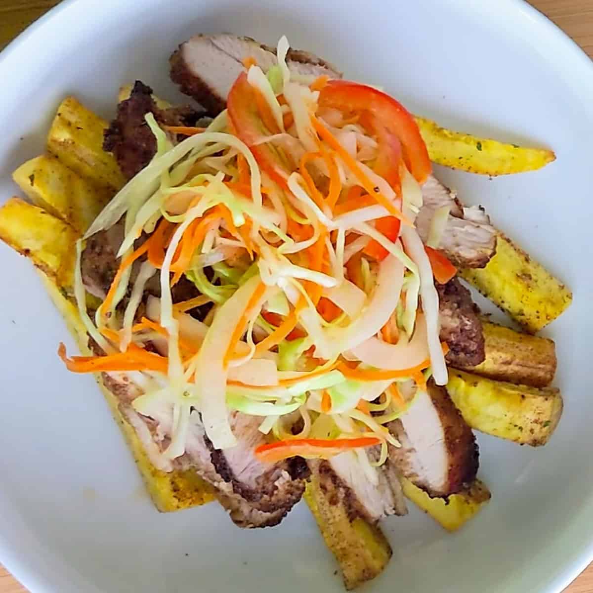 air fryer sliced chicken thighs and plantain fries topped with pikliz hot haitian peper cabbage slaw.