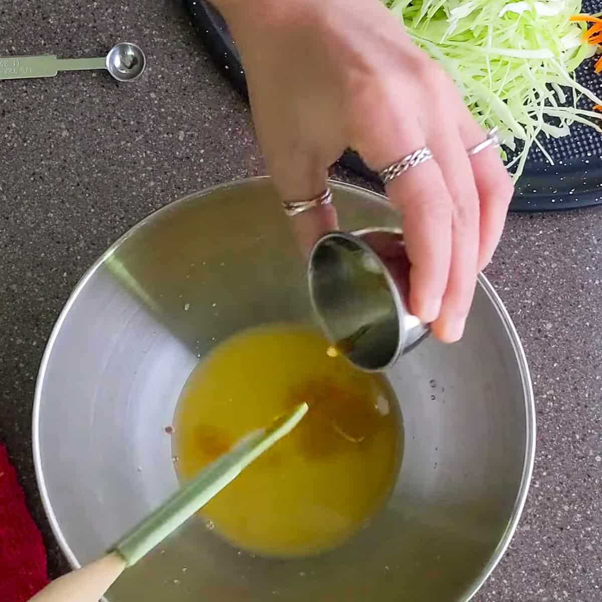 all liquids for the pikliz spicy slaw recipe being added to a mixing bowl.
