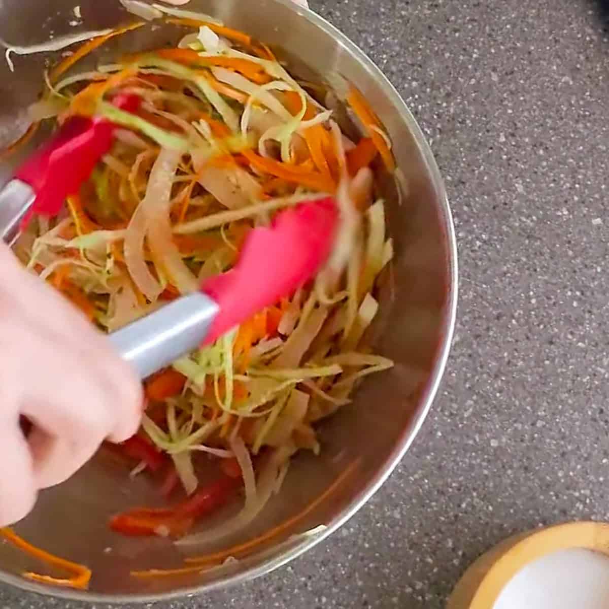 shredded vegetables added to a mixing bowl.