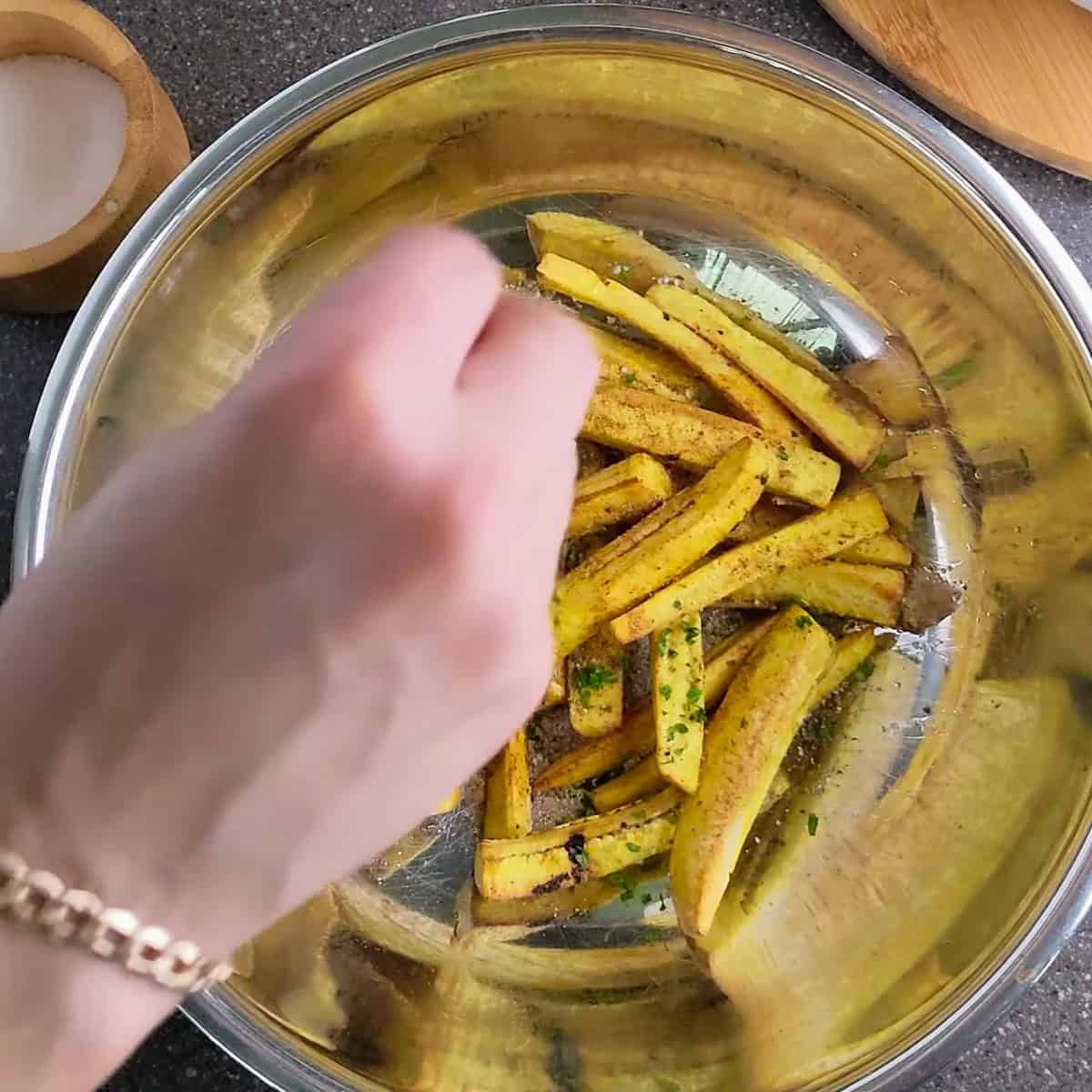 plantain fries being seasoned and garnished.