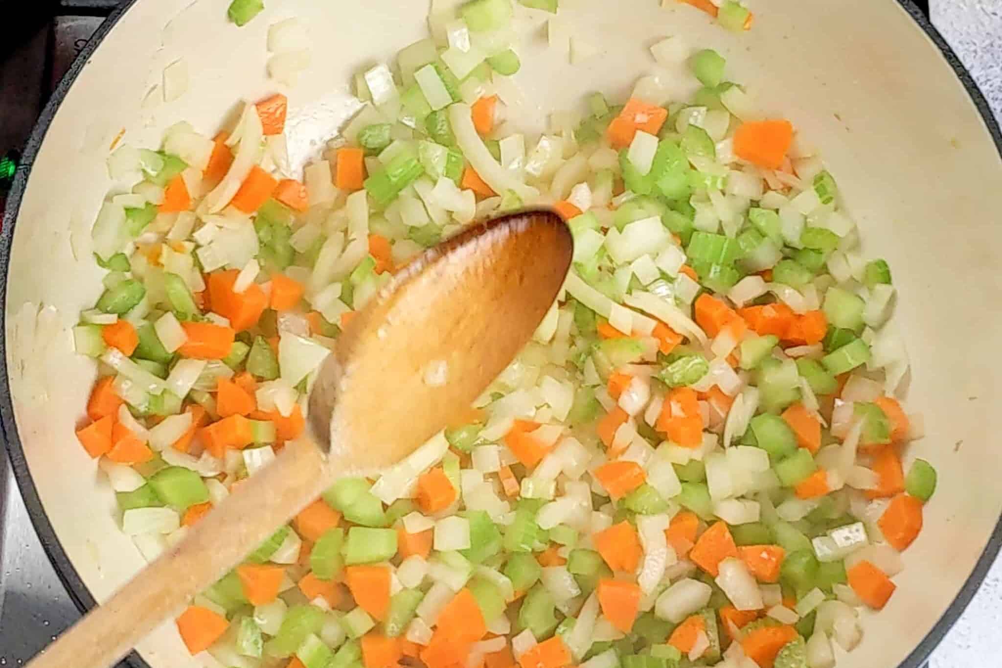 mirepoix of onion, carrots, and celery sweating in a Lodge 6 quart enameled Dutch oven