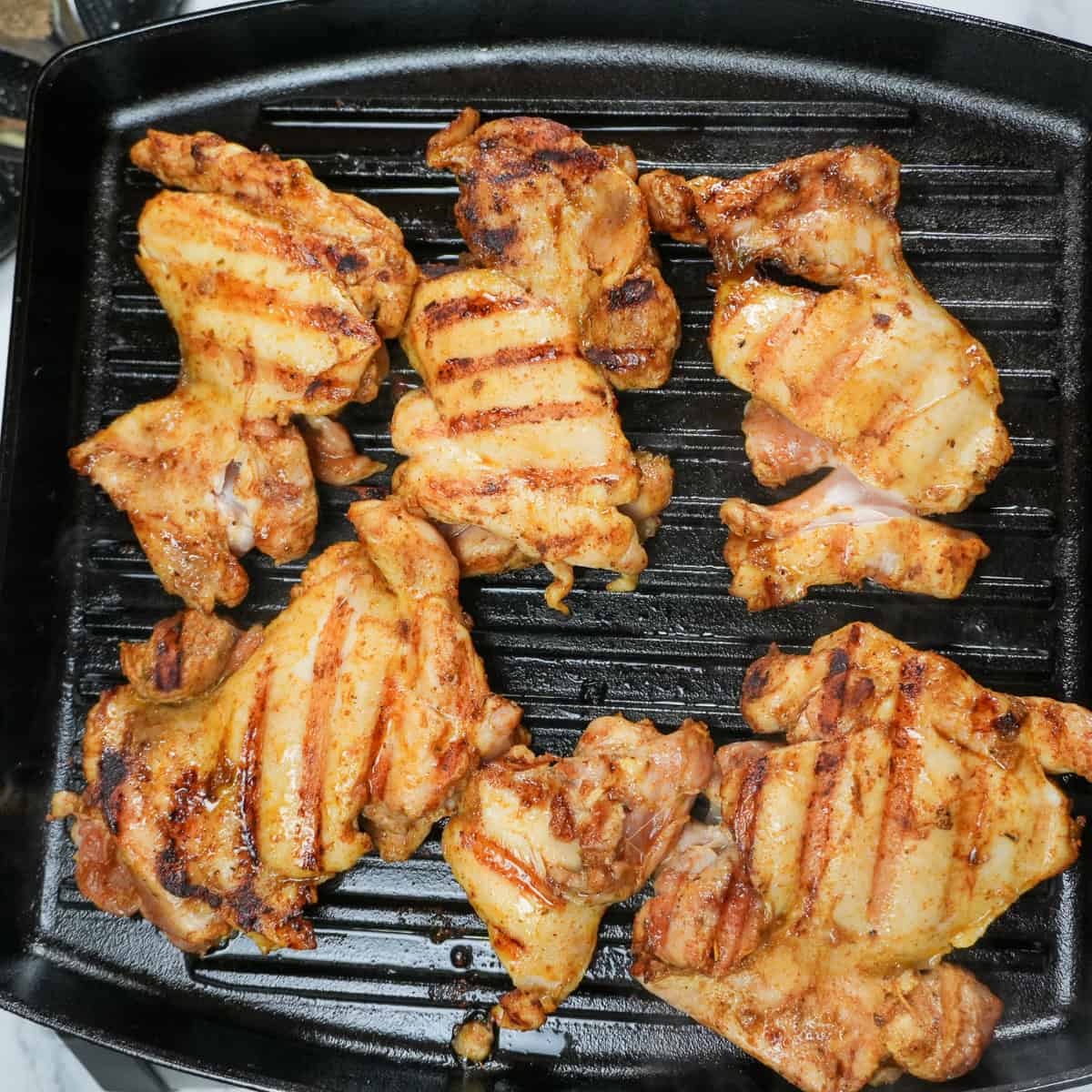 grilled chicken thighs on a cast iron grill pan.