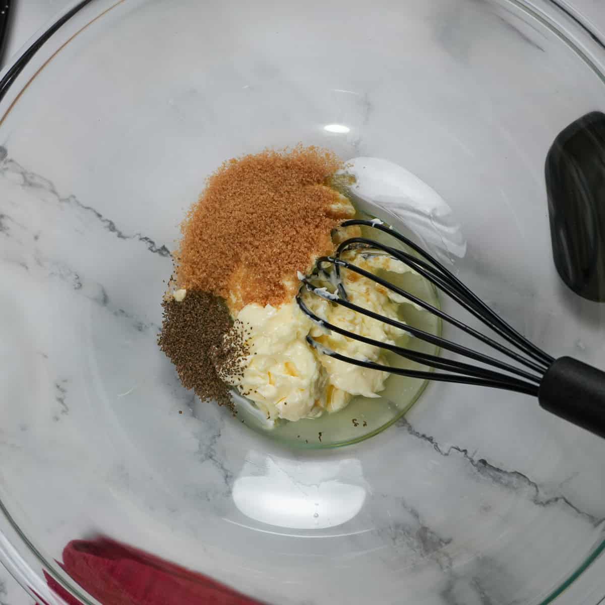 ingredinets for the coleslaw in a glass mixing bowl with a silicone whisk.