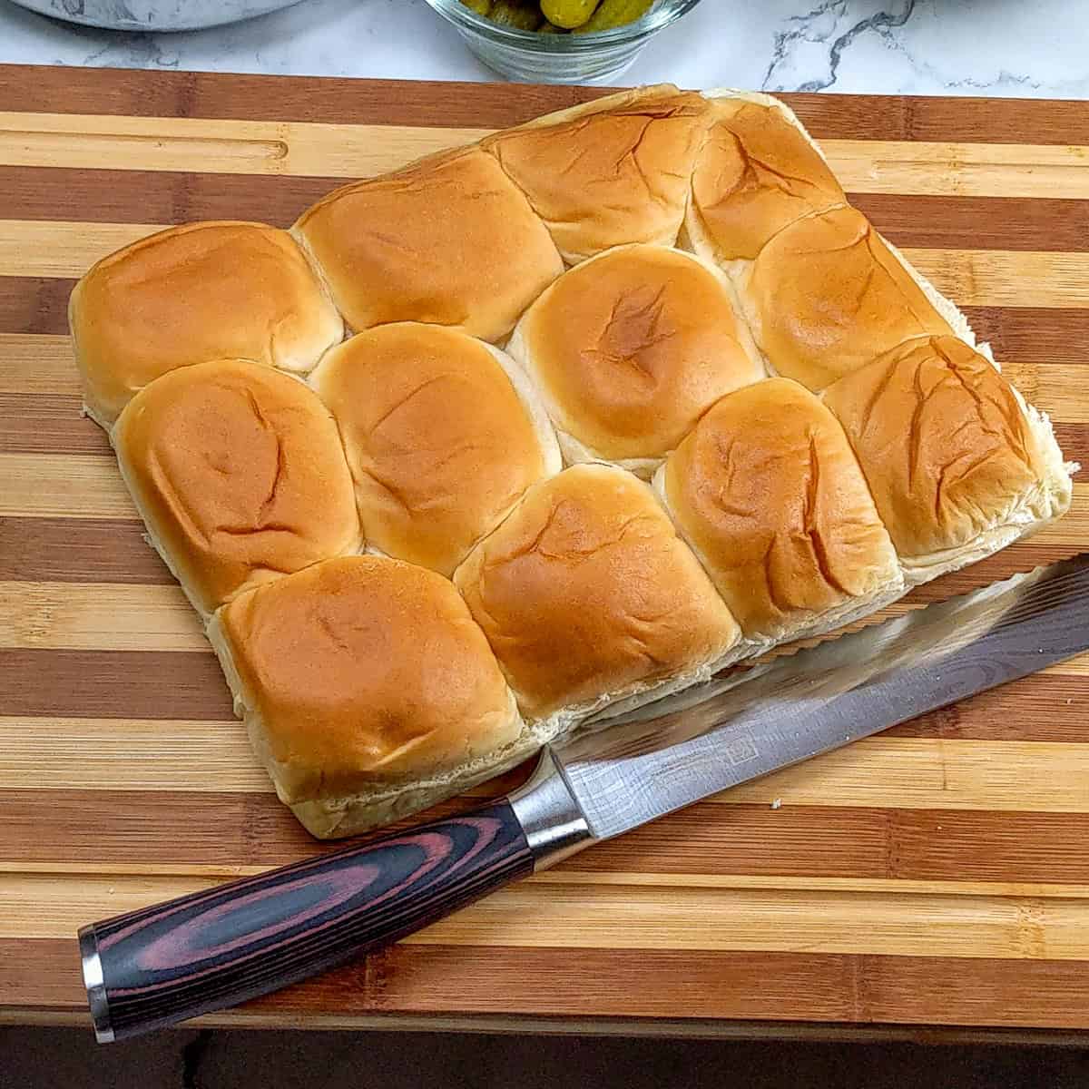 freshly sliced hawaiian sweet roll on a cutting board.