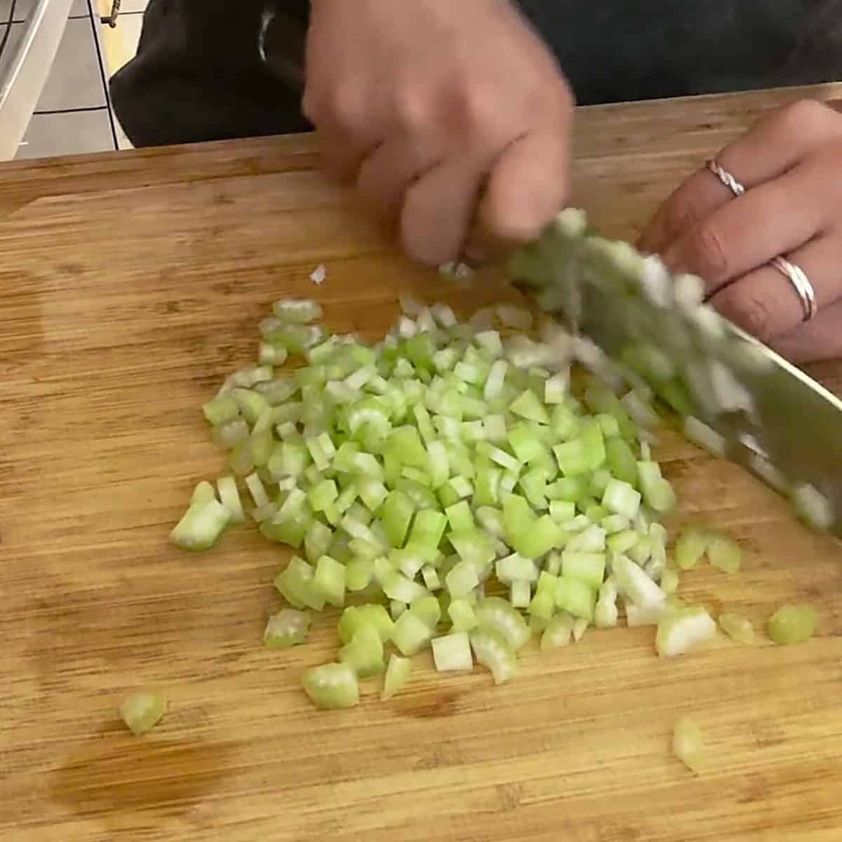 dicing celery on a cutting board.