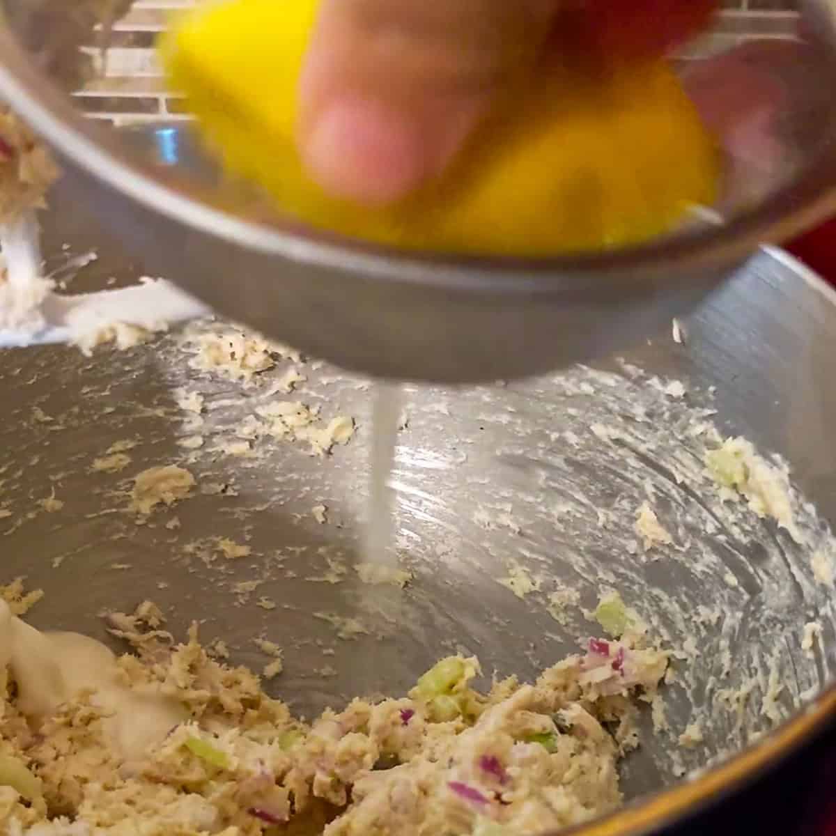 squeezing fresh lemon juice into mixing bowl.