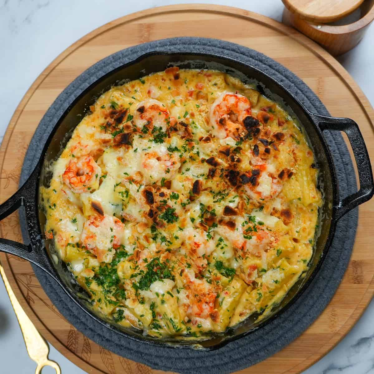 Broiled haitian style shrimp mac and cheese in a lodge cast iron blackock skillet.