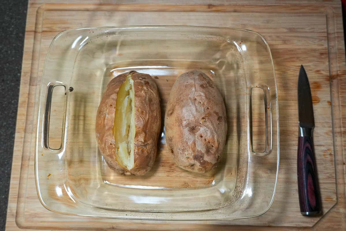 baked potatoes with slit in the middle in a baking dish.
