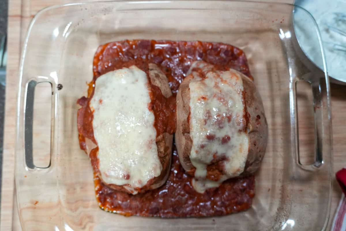 baked turkey chili baked potato with melted swiss cheese in a baking dish.
