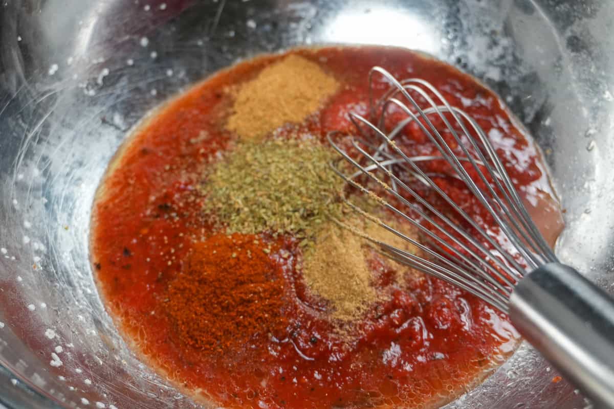 sauce ingredients (cumin, paprika, coriander, oregano and tomato sauce) for the mexican braised chicken dish.