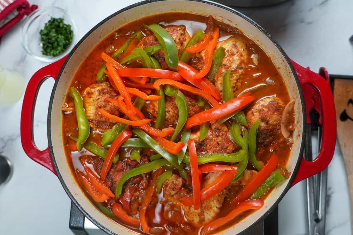 red and green sliced bell peppers on top of braised chicken.