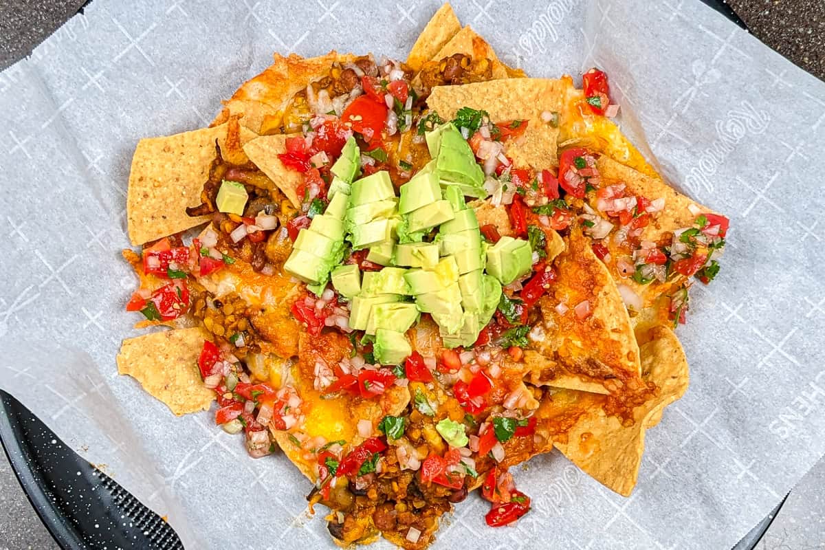 top view of the Protein-Packed Loaded Vegetarian Nachos topped with pico de gallo and fresh avocado chunks.