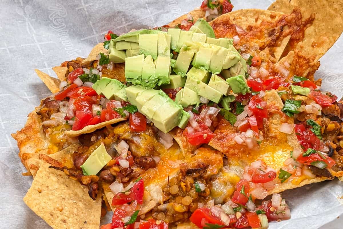 side view of the Protein-Packed Loaded Vegetarian Nachos topped with pico de gallo and fresh avocado chunks.
