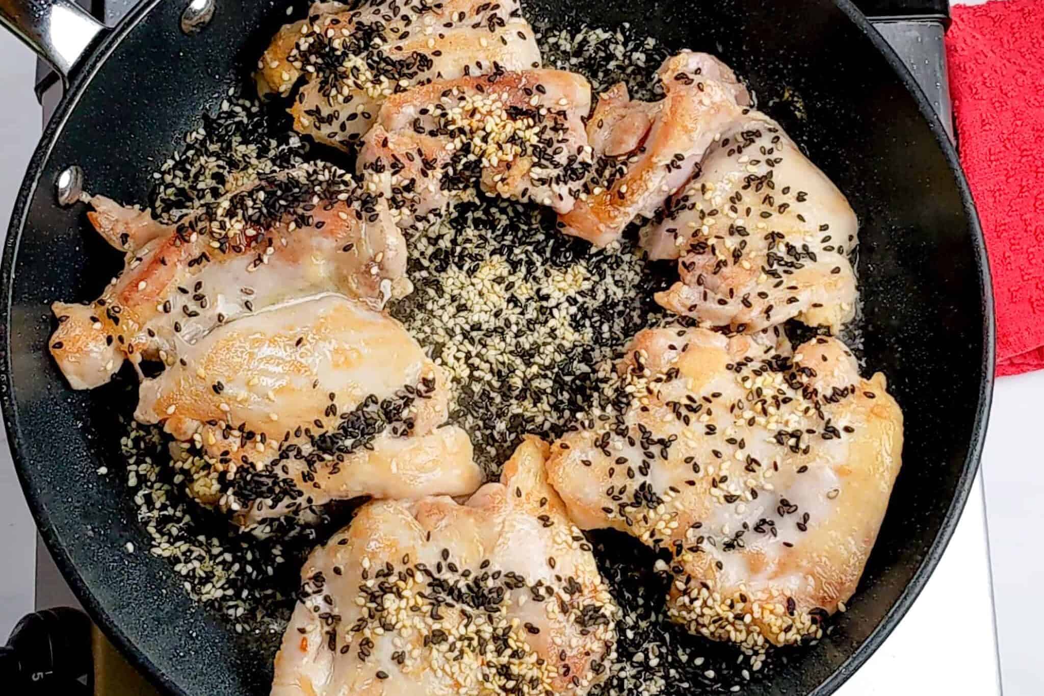 seared chicken breast with black and white sesame seeds in a non-stick frying pan