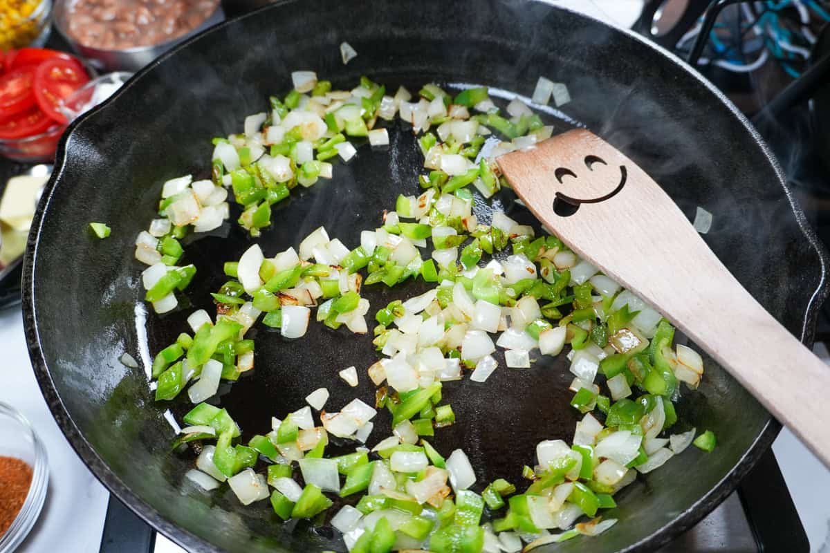 saluted onions and bell peppers in a cast iron skillet.