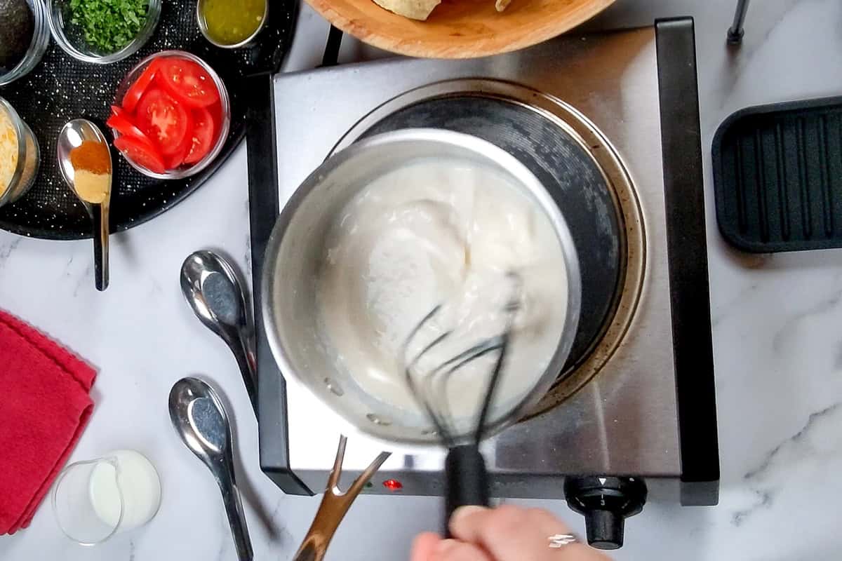milk added to the roux while being whisked with a flat silicone whisk.