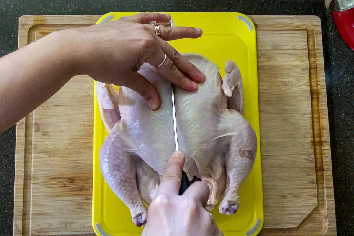 slicing the chicken in the middle of the breast bone.