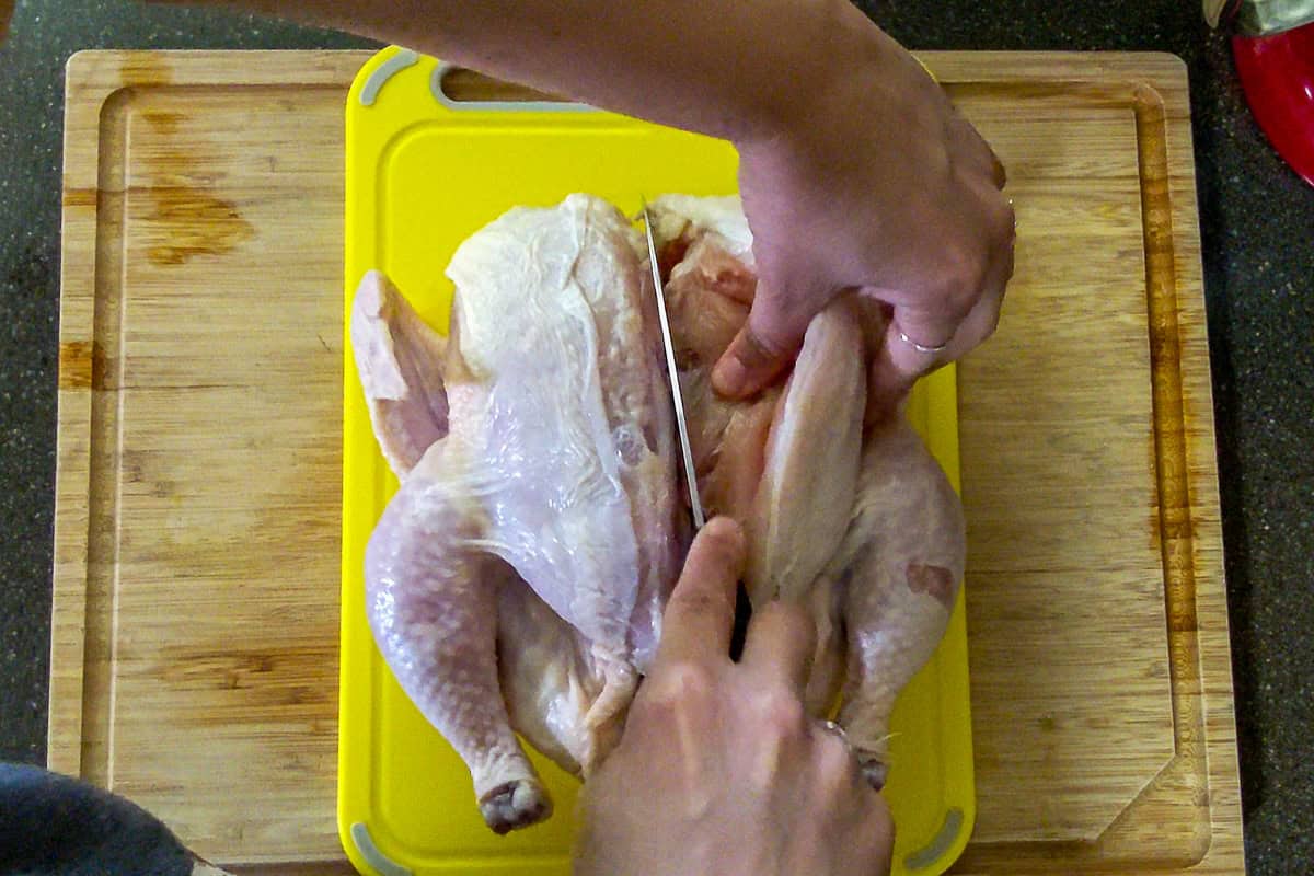 slicing against the bone to separate the chicken breast.