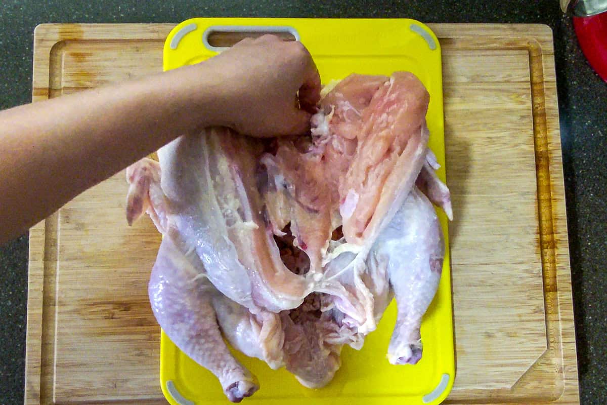chef showing where the joint bone for the wing and breast bone at the top of the chicken breast.
