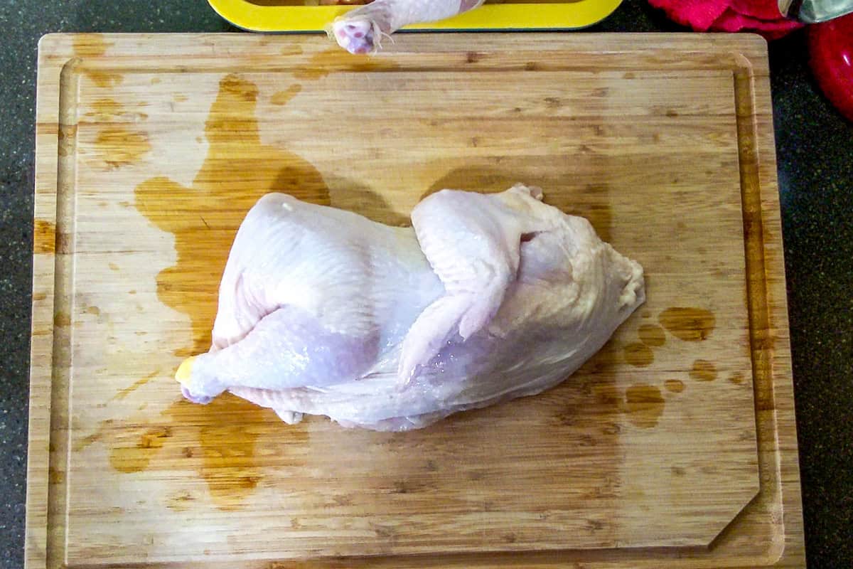 half of the whole chicken skin up on a wooden cutting board.