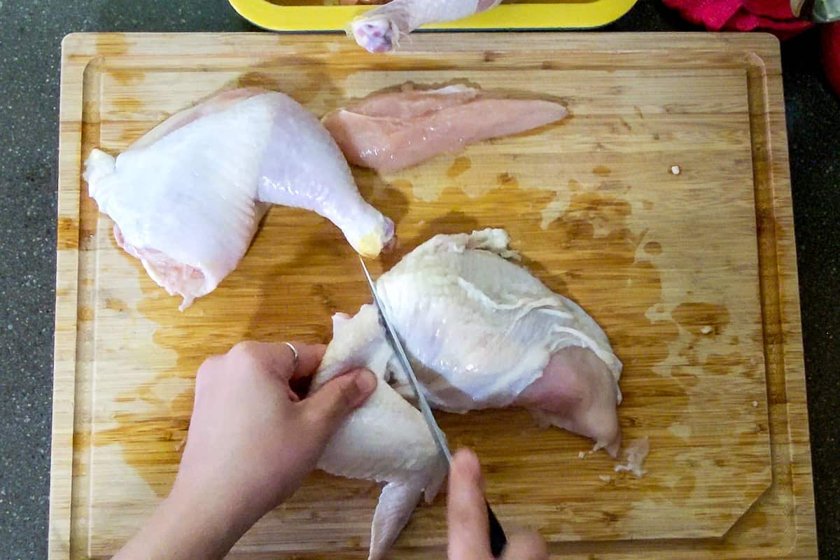 boning knife separating the chicken wing from the breast.