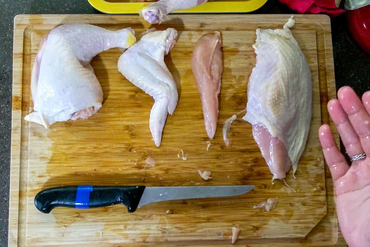 showing the chicken thigh and leg, whole wing, tenderloin, and chicken breast on the cutting board skin side up.