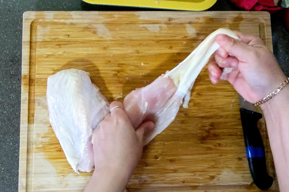 pulling the chicken skin off of the breast.