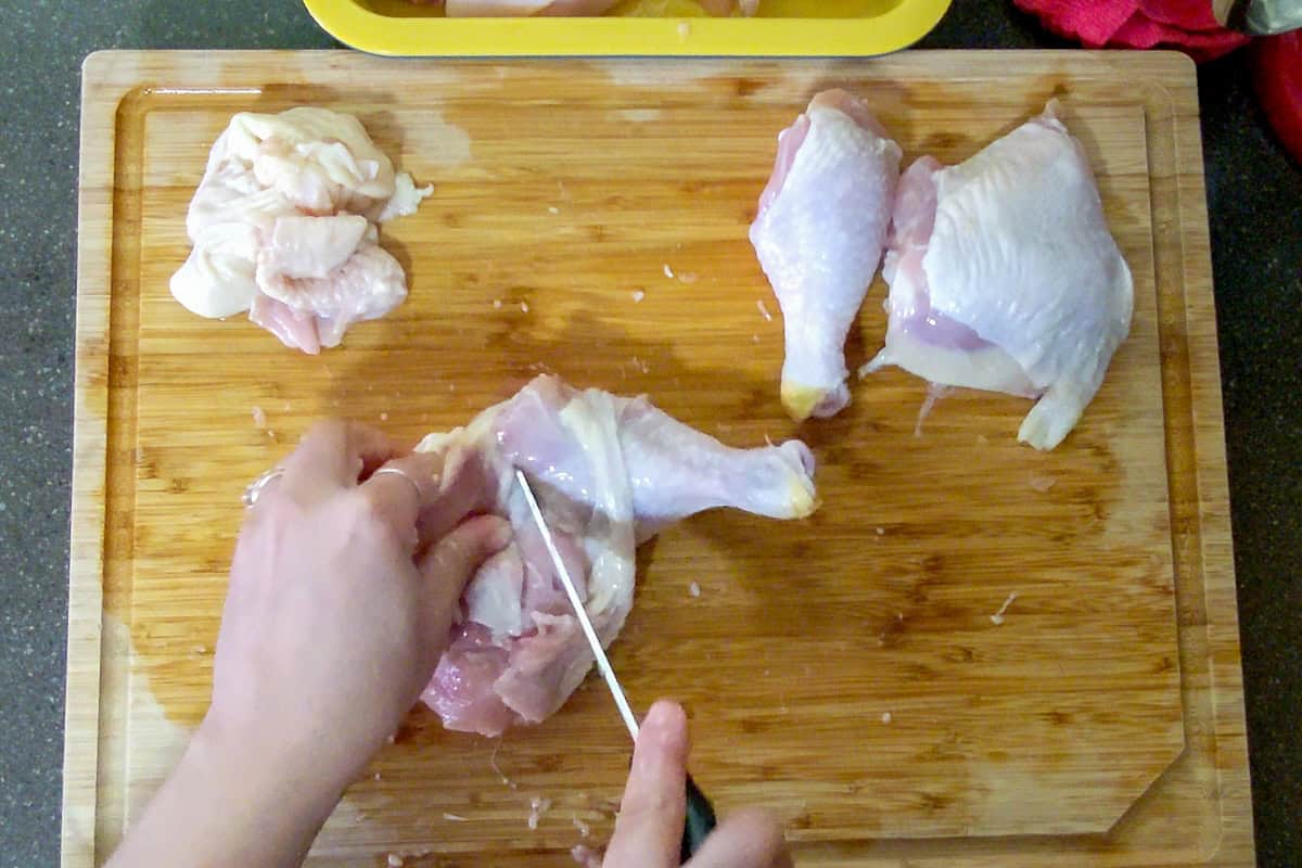 using the tip of the knife to separate chicken thigh from drumstick aka leg.