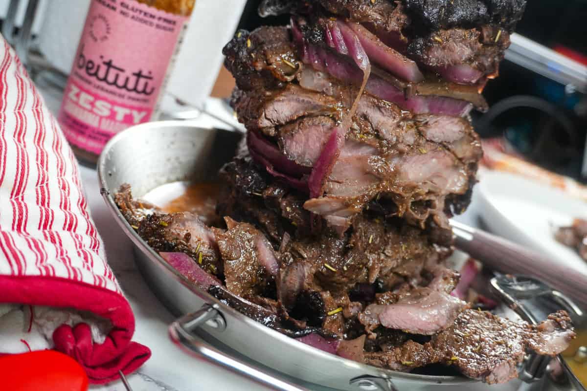 vertical skewered steak sliced with Beituti marinade bottle in the bakcground.