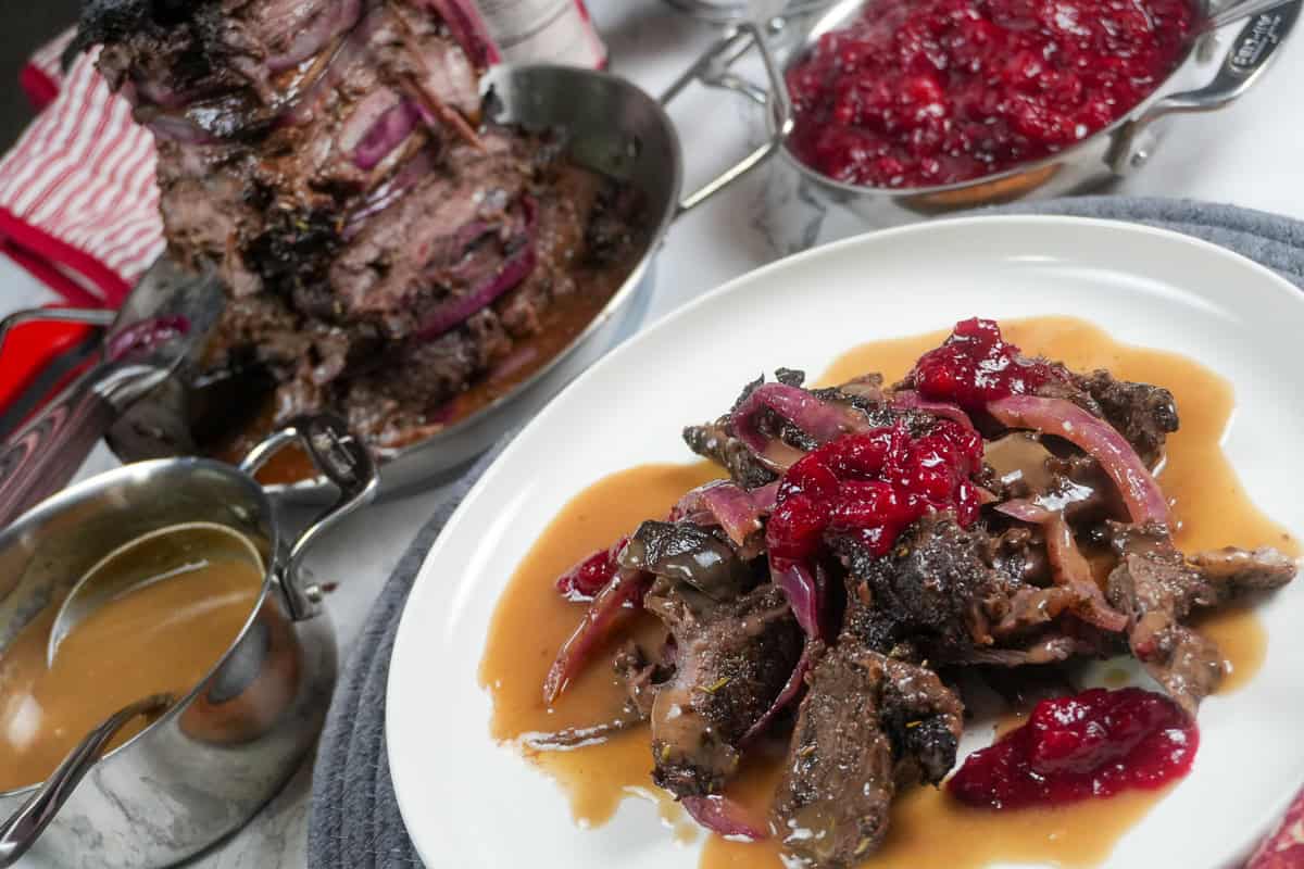 full layout of holiday steak shawarma plated next to a small decorative pot of gravy, beefs shawarma tower and cranberry chutney.