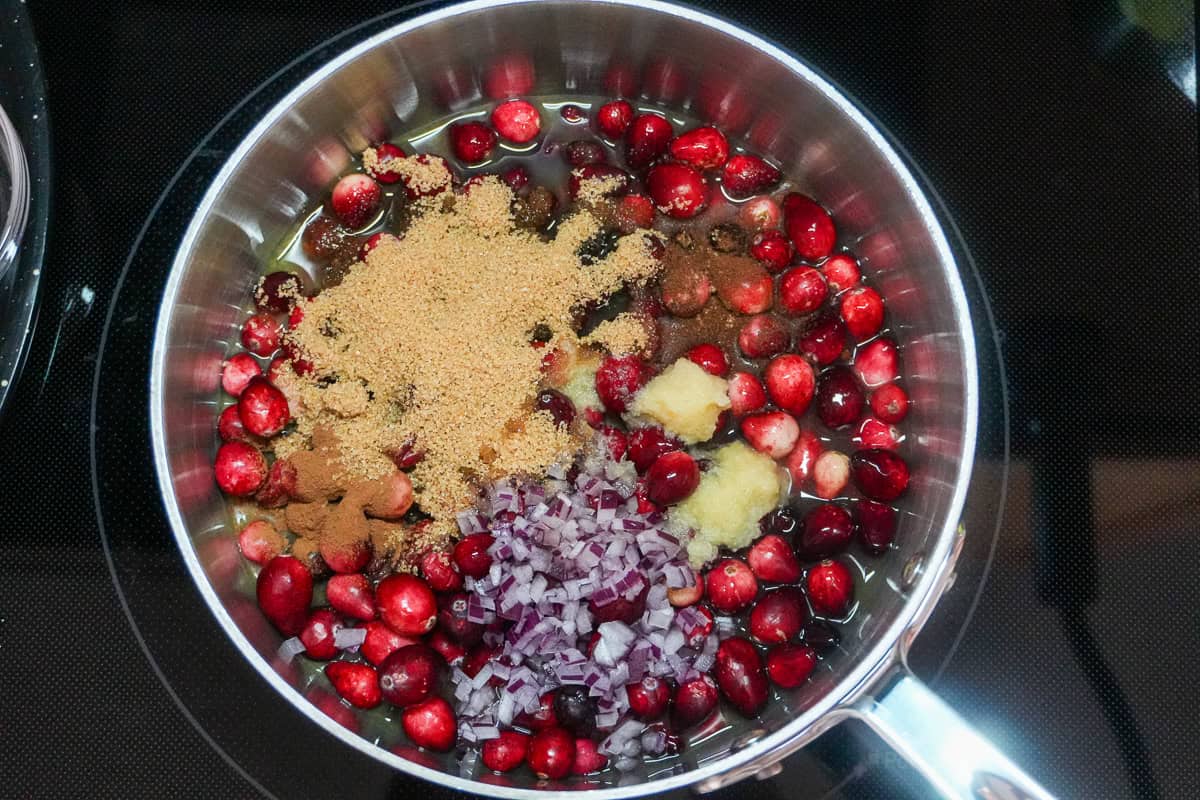 step one for the Fresh Cranberry Ginger Chutney with all ingredients in an all clad sauce pan.