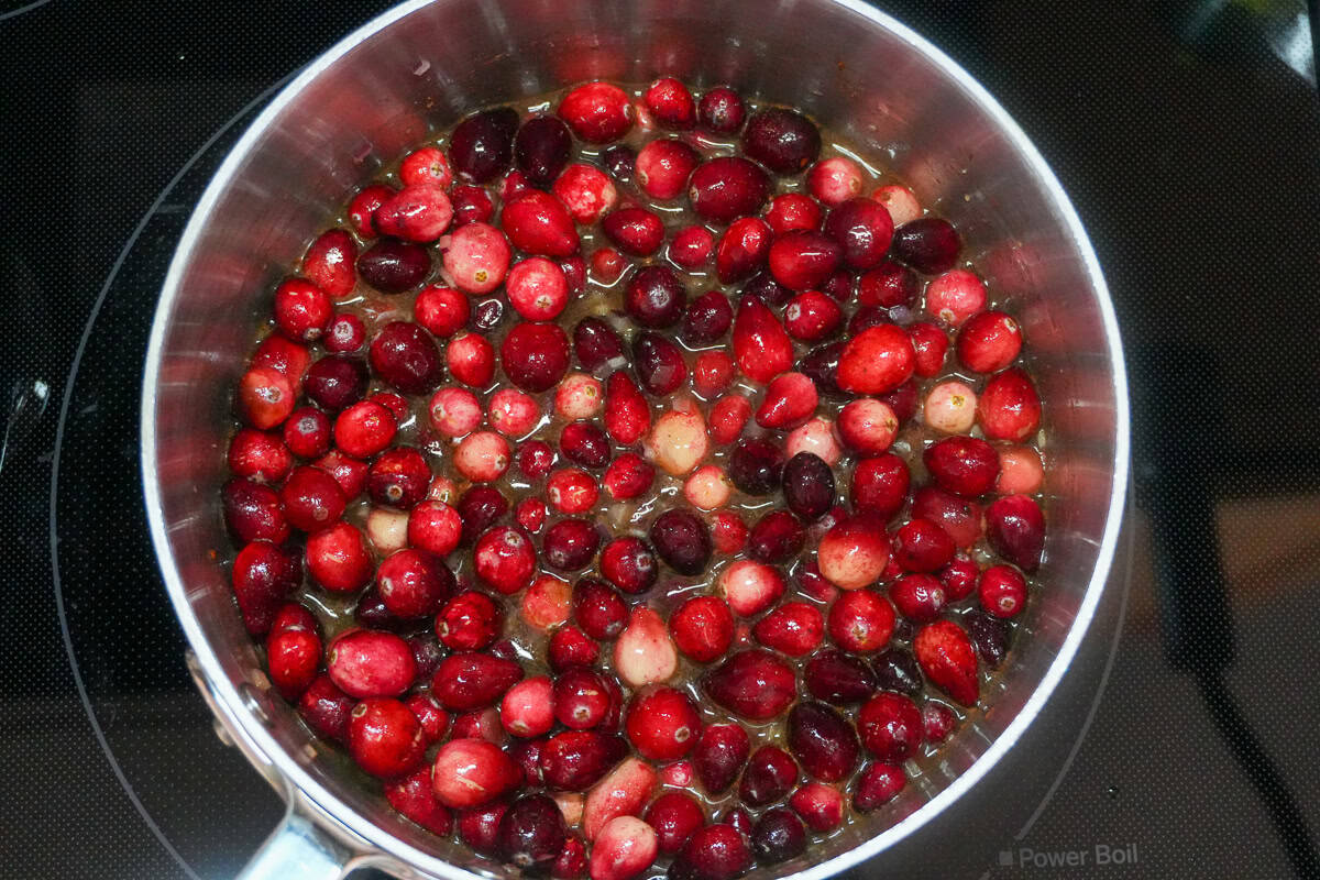 warmed fresh cranberries with ingredients in a sauce pan.