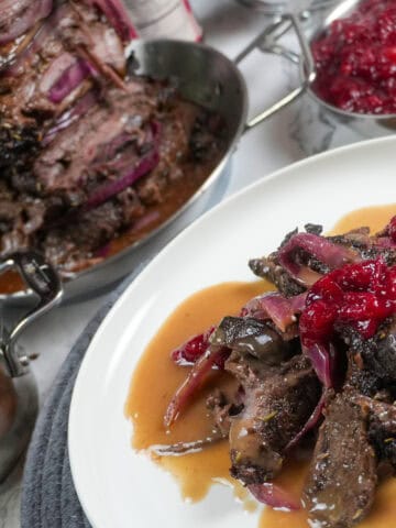 full layout of holiday steak shawarma plated next to a small decorative pot of gravy, beefs shawarma tower and cranberry chutney.
