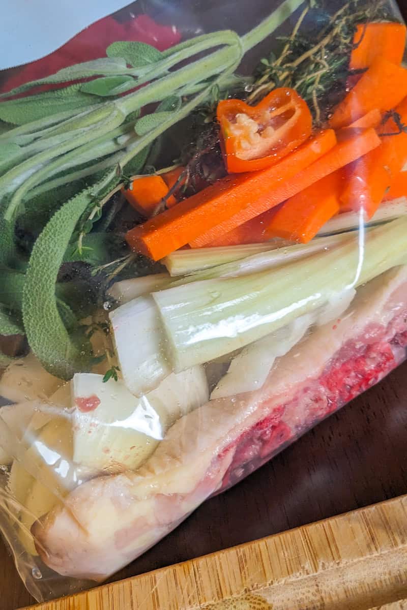 turkey gravy ingredients in a sealable bag with turkey back bone, herbs, aromatics and hot peppers.