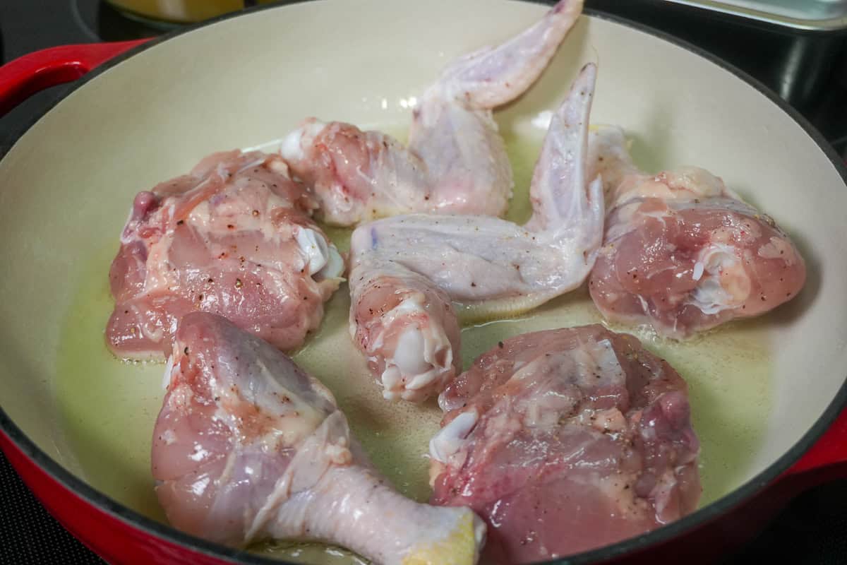 chicken pieces searing in a dutch oven.