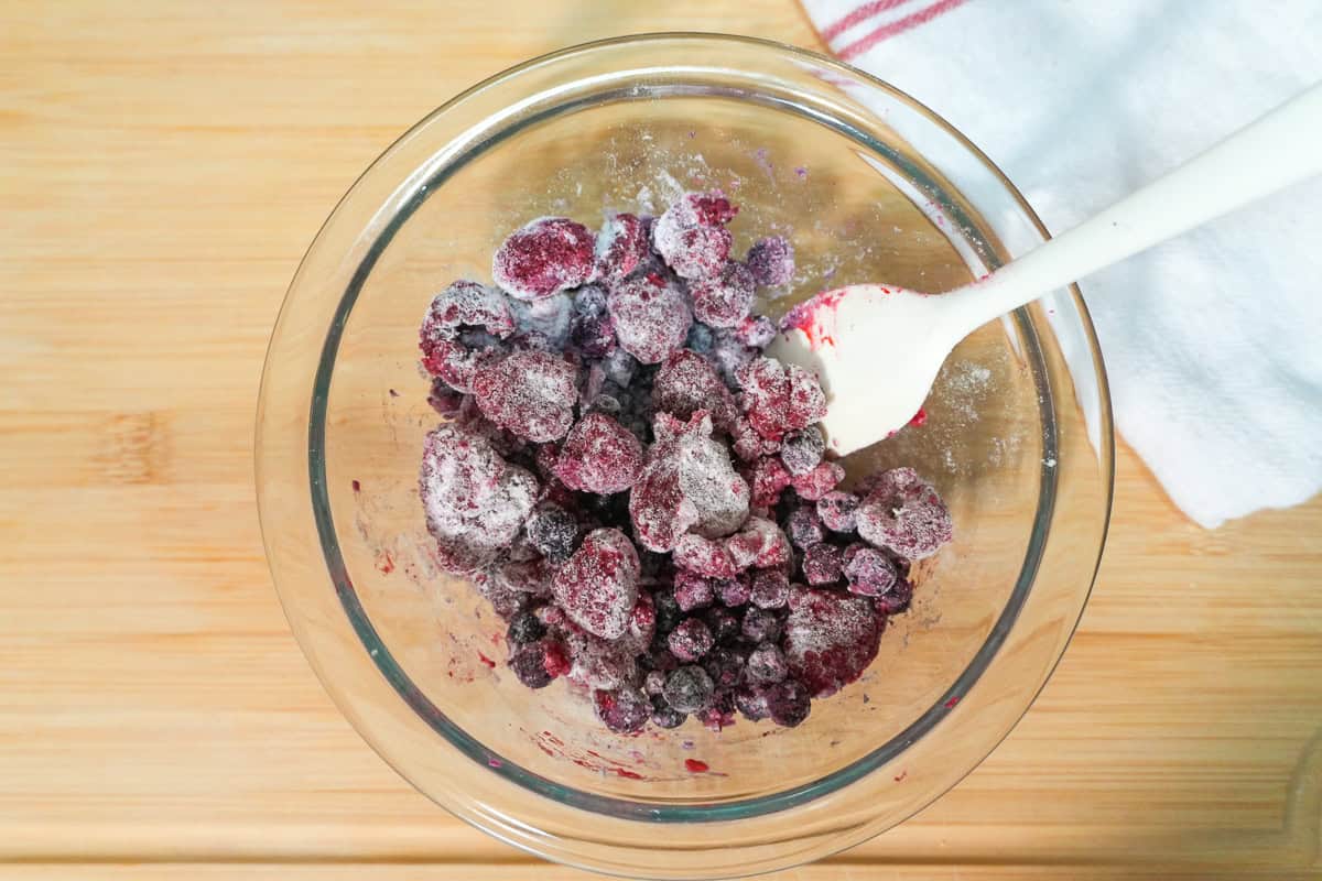 mixed berries tossed in flour in a pyex glass mixing bowl with a thermoworks spatula.