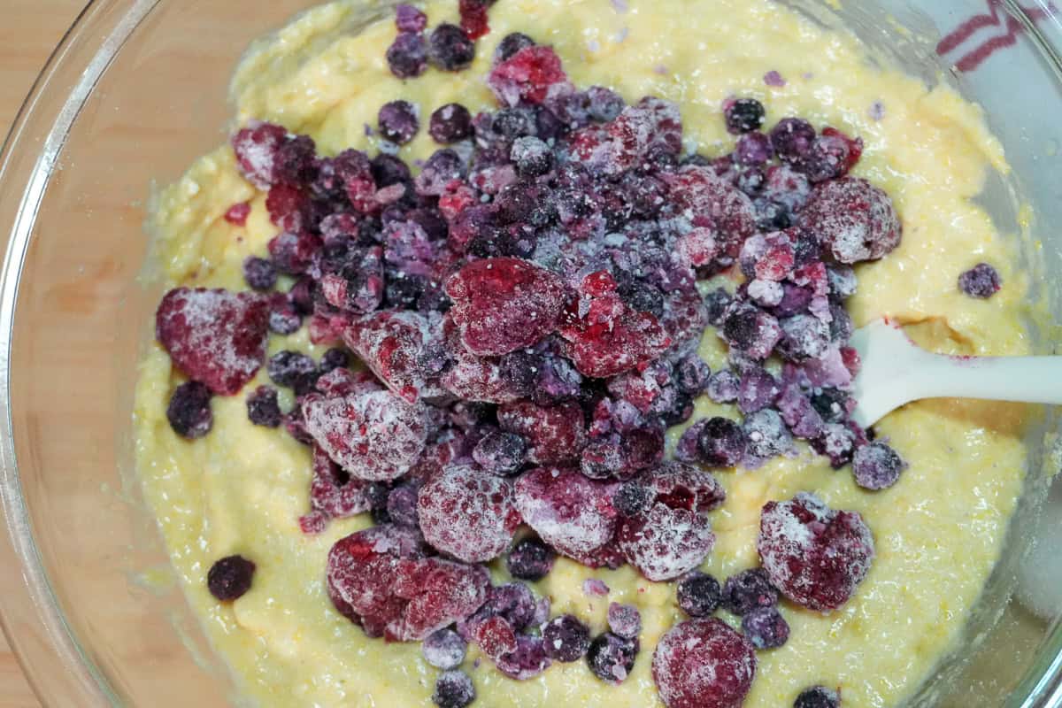 Banana Berry Corn Muffins with Yogurt batter topped with frozen berries tossed in flour.