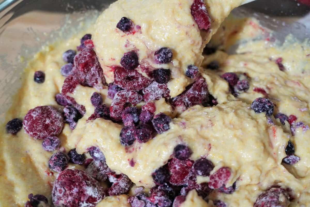 close up of spatula folding berries into batter.
