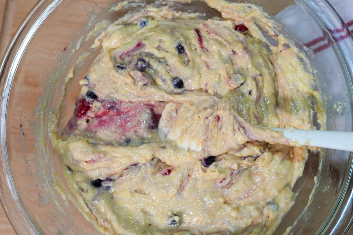 close up of spatula folding berries into batter.